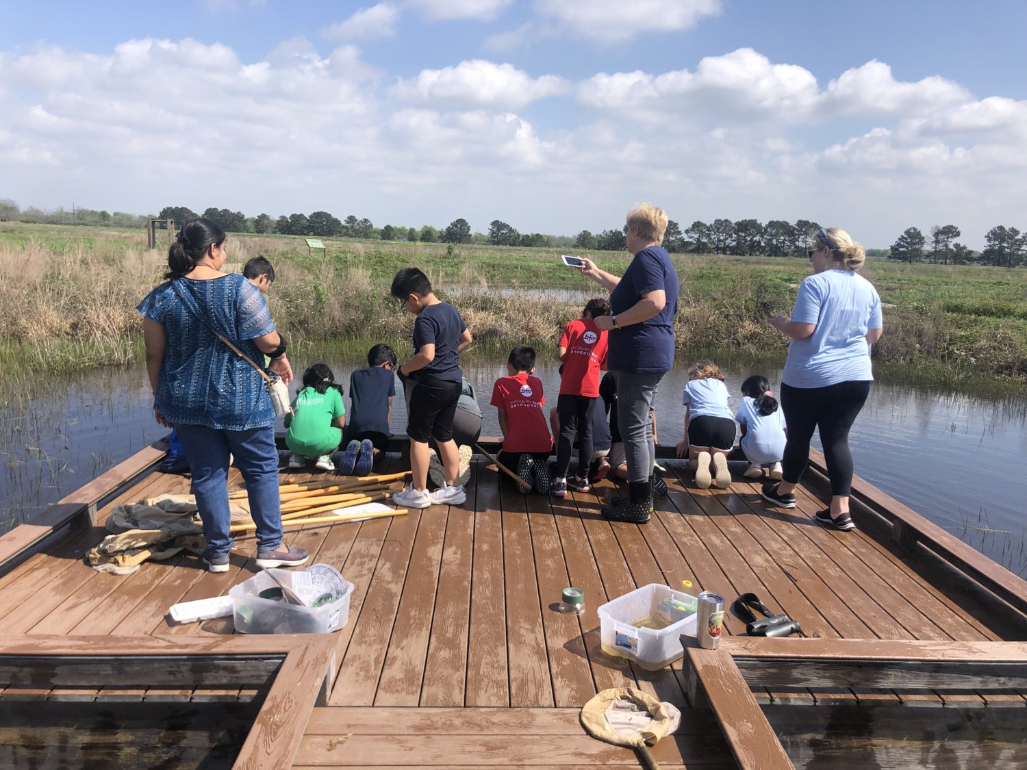 Students from Amy Campbell Elementary took a Feb. 9 field trip to the Coastal Prairie Conservancy, and were joined by their school’s namesake, Amy Campbell, second adult from right. Students are pictured doing their pond activity. This year’s TEKS require students to make seed balls and learn about ecosystems, and the preserve proved a good place to do those things.